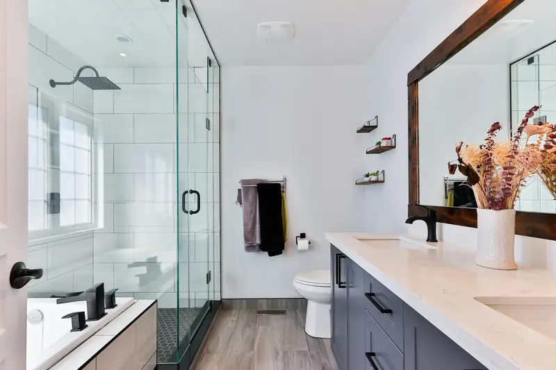 Modern bathroom with glass shower, wood floor and dark vanity